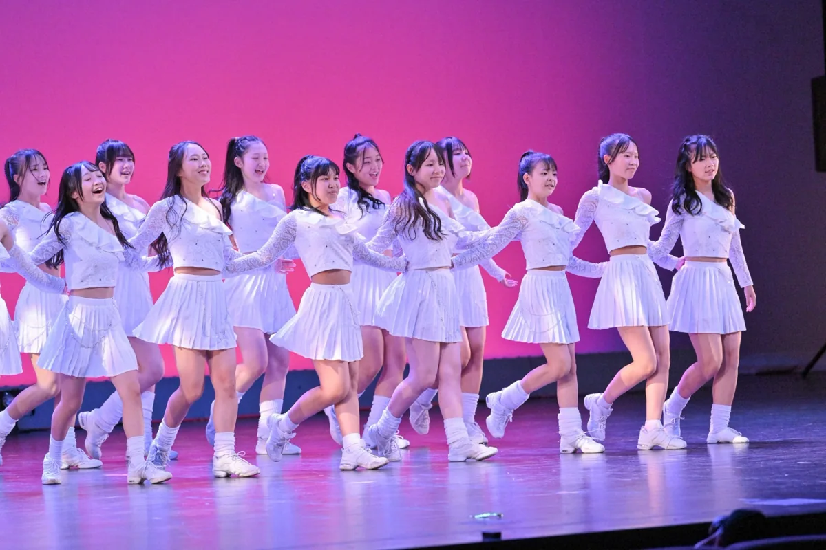 白い衣装で列を揃えて踊るステージ