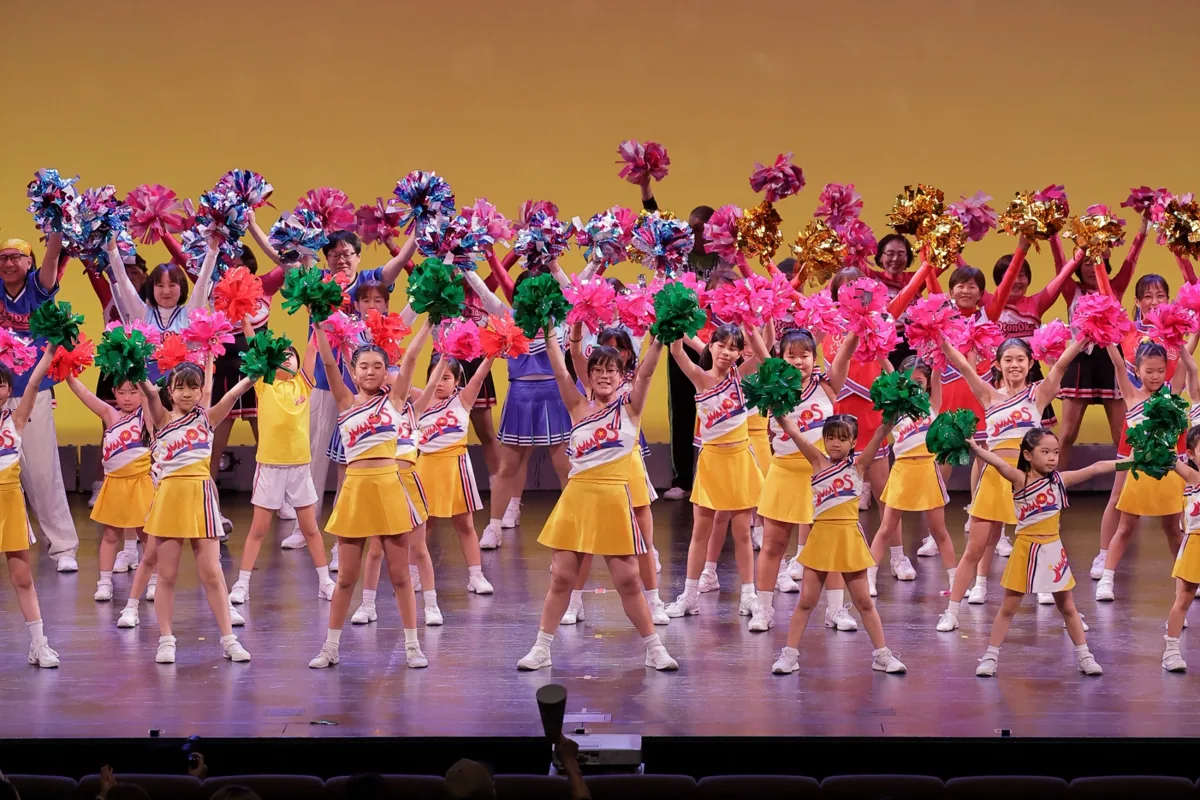 大勢の出演者がポンポンを掲げるフィナーレ
